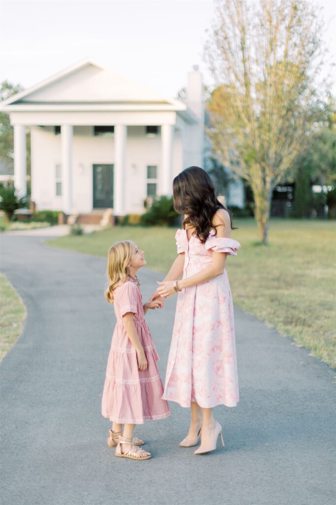 A heartwarming spring photo session capturing the bond between a darling mother and daughter. They are holding hands, surrounded by blooming flowers and the fresh vibrancy of the season. The image radiates love and connection in the embrace of springtime beauty.