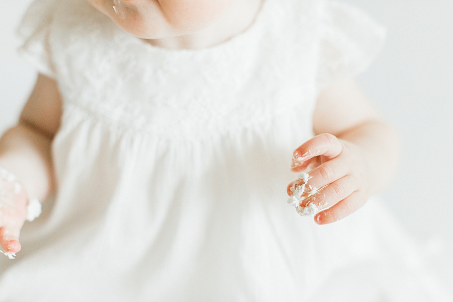 Detail of baby with frosting on her hands for cake smash